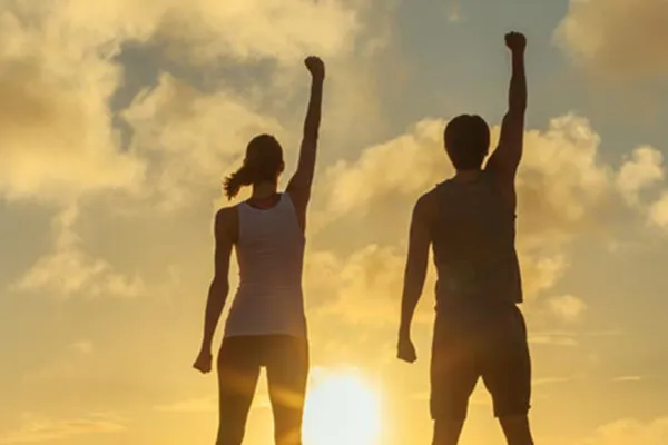 Ipamorelin-Peptide-Clinic A couple raise their right arms in the air in triumph, framed by the sunrise. Get Ipamorelin peptide treatment from Better Life Carolinas of Mount Pleasant in Charleston Metro.