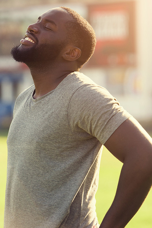 Lean-Muscle-and-Recovery-Treatment A black man in a gray t-shirt and smiles, looking up with closed eyes after a satisfying workout. Get treatment for lean muscle loss and recovery from Better Life Carolinas of Mount Pleasant in Charleston Metro.