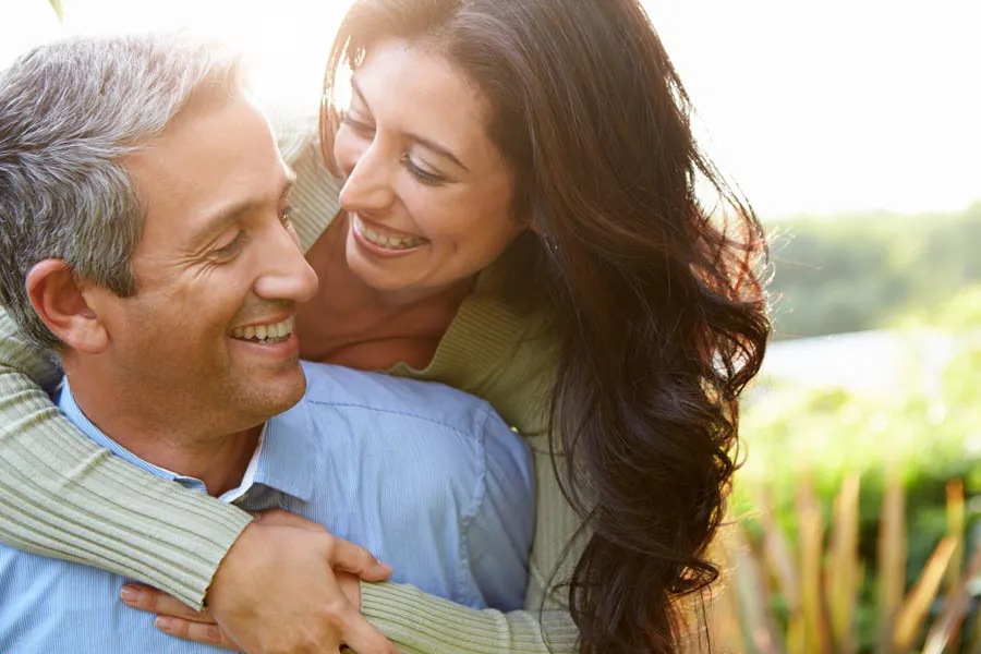 Longevity-Medicine-Clinic A middle-aged couple embracing and smiling in a meadow. Learn about the Longevity Program with Better Life Carolinas of Mount Pleasant in Charleston Metro.
