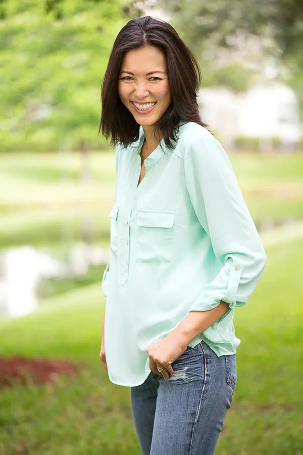 Perimenopause-Treatment A middle-aged brunette woman in a light green button-up shirt stands outside smiling, happy with her perimenopause treatment from Better Life Carolinas of Mount Pleasant in Charleston Metro.